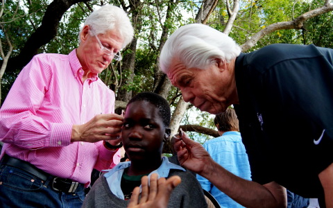 President Bill Clinton and Bill Austin, founder of the Starkey Hearing Foundation, fit a patient with hearing aids at a mission in Zambia in August 2013 (Photo: Starkey Hearing Foundation)