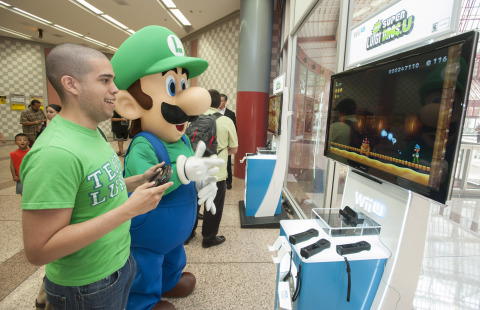 In this photo provided by Nintendo of America, Luis D. of Chicago enjoys playing New Super Luigi U at the Clark/Lake 'L' Station in Chicago on Aug. 12, 2013. A Chicago 'L' train's interior and exterior are wrapped with a Luigi theme through Sept. 8 in celebration of the Year of Luigi and New Super Luigi U, which launches as a packaged game for Wii U on Aug. 25, 2013. (Photo by Peter Barreras/Invision for Nintendo/AP Images)