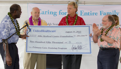 Tony Welters (left), executive vice president, UnitedHealth Group; Vice Admiral (Ret.) John Mateczun (left center), chief medical officer, UnitedHealthcare Military & Veterans, present a $250,000 grant check to Howard Ainsley  (right center), East Hawaii Region CEO of Hilo Medical Center, as Hawaii Gov. Neil Abercrombie (right), applauds. UnitedHealthcare, a UnitedHealth Group (NYSE: UNH) company, has awarded a $250,000 grant to support the primary care training program to help enhance primary care services for East Hawaii residents, including members of the United States military and their families, and to help train the next generation of physicians. (Photo: Eugene Tanner)
