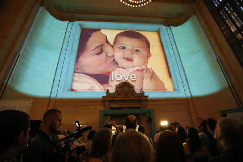 Guests watch as the 3-D photo installation is unveiled at the Pampers "Love, Sleep & Play" launch event at Grand Central Terminal, on Wednesday, August, 21, 2013 in New York City, New York. Pampers' newest campaign celebrates the unique ways babies experience love, sleep and play. 
