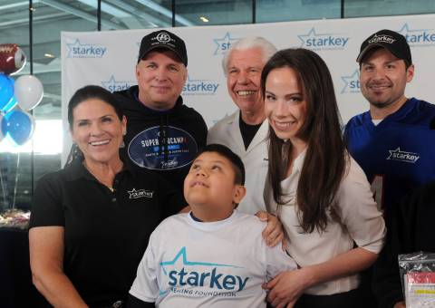 IMAGE DISTRIBUTED FOR STARKEY HEARING FOUNDATION - Tani Austin, left, co-founder Starkey Hearing Foundation, Garth Brooks, second left, Bill Austin, center, Founder of Starkey Hearing Foundation, Barbara Bush, second right, and Steven Sawalich, Senior Executive Director, Starkey Hearing Foundation, pose with William Romero, 7, of Brooklyn, after he received free hearing aids at the Foundation's hearing mission, Saturday, Feb. 1, 2014, at Yankee Stadium in New York. (Photo by Diane Bondareff/Invision for Starkey Hearing Foundation/AP Images)