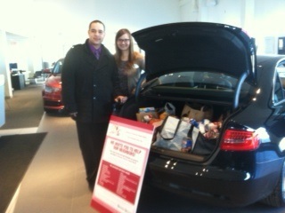 Audi of Stratham sales personnel Nigel Reed (L) and Brandee Connor (R) get ready to deliver the dealerships non-perishable food donations. (Photo: Business Wire)