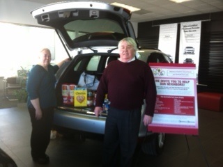 Porsche Stratham employees Janice Thomas (L) and Harry Robinson (R) get ready to deliver the dealerships non-perishable food donation. (Photo: Business Wire)