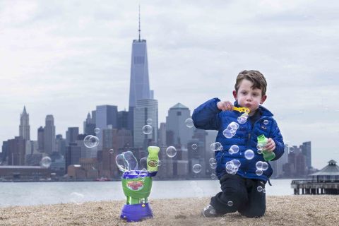 Benjamin Winston, 4, blows bubbles alongside the Typhoon 2.0 bubble machine and against the backdrop of New York City as he prepares for National Bubble Week, an event celebrated by Gazillion Bubbles to herald the arrival of spring, Friday, March 14, 2014, in Hoboken, N.J. (John Minchillo/AP Images for Gazillion Bubbles)