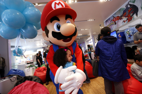 In this photo provided by Nintendo of America, Namira A., of Brooklyn, meets Mario at an exclusive media event at Nintendo World on Saturday, April 26, 2014, in New York. Attendees had the opportunity to meet characters and play new games, such as Mario Golf: World Tour, Kirby: Triple Deluxe and Tomodachi Life, for the portable Nintendo 2DS hand-held system. Nintendo 2DS is the perfect entry point into the Nintendo hand-held experience and maintains many of the same hardware features as Nintendo 3DS. (Photo by Jason DeCrow/Invision for Nintendo/AP Images)