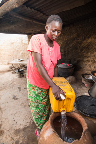 A woman in Ouagadougou, Burkina Faso, fills up a water storage container with safe water for her hom ... 