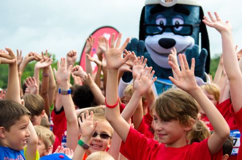 More than 150 youth join UnitedHealthcare's mascot Dr. Health E. Hound at the starting line for warm-up stretches and exercises at the UnitedHealthcare IRONKIDS Kansas Fun Run at Clinton State Park. UnitedHealthcare sponsored the race and made a $3,000 donation to the Boys & Girls Club of Lawrence in support of youth healthy living programs and provided free race entries. Source: Kelly Prier.