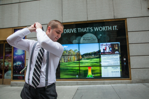 A Wall Street passerby swings through Mohegan Sun's Interactive golf-themed advertising campaign. (Photo: Business Wire)