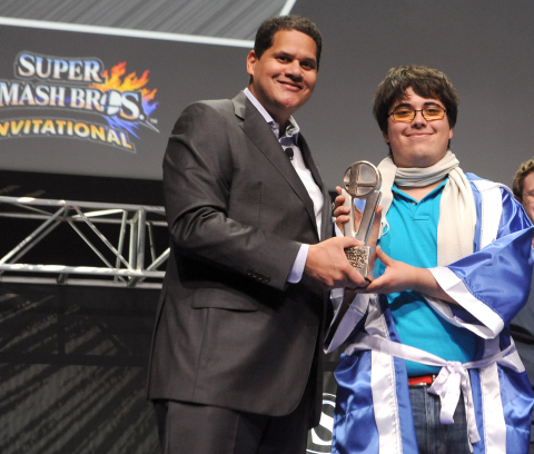 In this photo provided by Nintendo of America, Super Smash Bros. Invitational winner Gonzalo “ZeRo” Barrios of Chillan, Chile receives the grand-prize trophy from Nintendo of America President and COO Reggie Fils-Aime. Thousands of fans in the audience and countless more watching online celebrated the Super Smash Bros. franchise in anticipation of the game’s launch this year on both Nintendo 3DS and Wii U. (Photo: Business Wire)