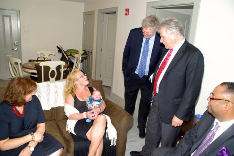 Robin DePaiva (sitting) shows off her newborn baby Patrick in the living room of her new apartment at Gini's House, a new, permanent supportive housing community for women and their families in Norwalk. L to R: Maria Gordon Shydlo, UnitedHealthcare; DePaiva and her son Patrick; Ross Burkhardt, President & CEO of New Neighborhoods Inc.; Charlie Werhane, President & CEO, Enterprise; and Alan Mathis, President & CEO, Liberation Programs (Photo: Chris Bosch).