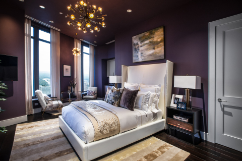 The master bedroom is dressed with a dramatic plum wall color layered with luxe furnishings in hues of gold and ivory, evoking modern elegance and glamour.(Photo: Business Wire)