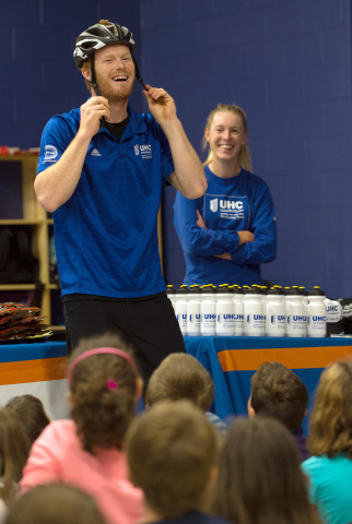 UnitedHealthcare Pro Cycling team member John Murphy shows children at the Boys and Girls Clubs in Warwick, R.I., how to correctly put on a bike helmet as fellow cycling team member Hannah Barnes, right, looks on during a visit to the club to talk about cycling safety, fitness and nutrition, Friday, Sept. 19 (Photo: Gretchen Ertl).