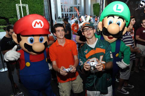 In this photo provided by Nintendo of America, Mario and Luigi cheer on a heated Super Smash Bros. for Wii U battle outside the University of Miami vs. Florida State University football game on Nov. 15, 2014. The Super Smash Bros. for Wii U game, launching on Nov. 21, 2014, is the first fighting game in the series to allow eight local players to play simultaneously.