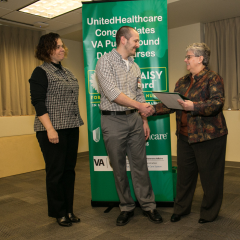 Melissa Barnes, vice president, The DAISY Foundation (left) and Barb Hostetler, RN, Director of Regional Clinical Services, Northwest Region, UnitedHealthcare Military & Veterans (right) present The DAISY Award to Joseph Smith, RN, at a special ceremony today at VA Puget Sound Health Care System in Seattle (Photo: Kim Doyel).