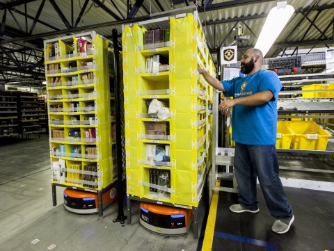 An Amazon employee picks items from a Kiva robot. (Photo: Business Wire)