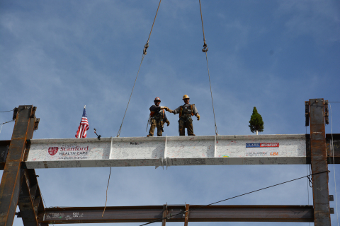 Two iron workers place the ceremonial beam onto the new Stanford Hospital. (Photo: Business Wire)