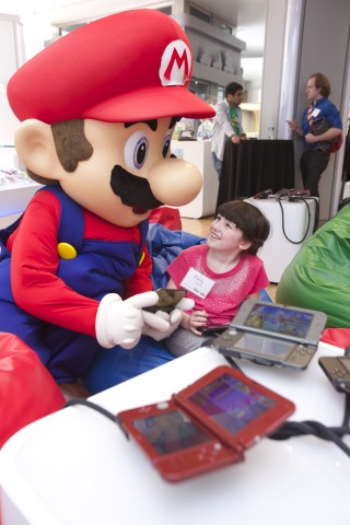 In this photo provided by Nintendo of America, Emily S., age 8, of New York, meets Mario at an exclusive event at the Nintendo World store in New York on April 25, 2015. Attendees were delighted with a surprise visit by the Mario costumed character and played Puzzle & Dragons Z + Puzzle & Dragons Super Mario Bros. Edition, two surprisingly deep puzzle games that combine elements of match-three and RPG games, and that will come in one package to the Nintendo 3DS family of systems on May 22.