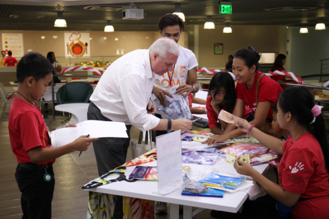 Wells Fargo Enterprise Global Services, LLC - Philippines Chief Administrative Officer Denis McGee buys handmade shirts from beneficiary school students during the Fundraising Week. (Photo: Business Wire)