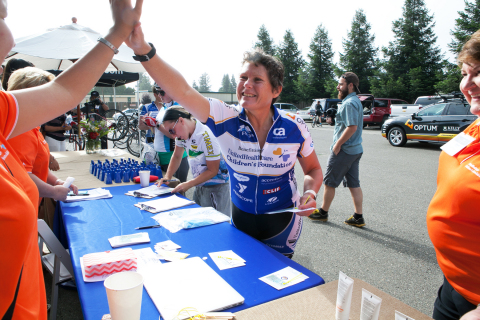 Cyclist Pip Bond high-fives a volunteer prior to the start of the inaugural Velo & Vines Century Ride in Healdsburg, Calif. The event kicked-off at the Arnot-Roberts winery and is raising funds for the UnitedHealthcare Children's Foundation. The foundation provides medical grants to help children gain access to health-related services not covered, or not fully covered, by their parents' commercial health insurance plan. Last year, UHCCF awarded about $5.4 million in medical grants to more than 2,000 children across the country. (Photo credit: Amy Sullivan)