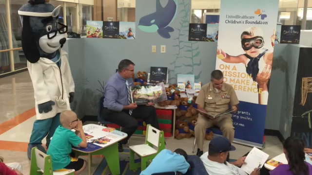 Commanding Officer Capt. Acosta of the Naval Medical Center San Diego (NMCSD) is joined by Tom Chohany of UnitedHealthcare and mascot Dr. Health E. Hound as they read to a group of children from the popular Oliver & Hope children’s storybook to young patients at the pediatric intensive care unit. UnitedHealthcare is donating 40 UnitedHealthcare Children’s Foundation (UHCCF) reading stations and nearly 1,000 Oliver & Hope books as part of a summer reading initiative to health clinics, medical centers and doctor’s offices throughout San Diego to encourage early reading and healthy living among children. NMCSD is receiving 10 reading stations, as well as books and children’s activity booklets, which will be placed in patient waiting areas in the hospital (Video: Kevin Herglotz).