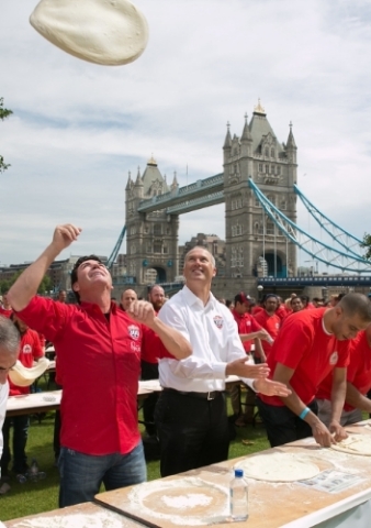 John Schnatter, Founder of Papa John's, demonstrates how a skilled pizza maker tosses dough. (Photo: Business Wire)