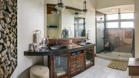 The Blog Cabin luxurious master bathroom features a double sink vanity and a large walk-in, glass-enclosed shower. A combination of stunning tile is the hallmark of the room whose color palette is dictated by the serene outdoor vistas. (Photo: Business Wire)