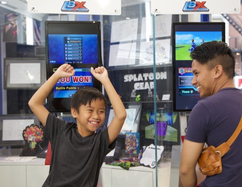In this photo provided by Nintendo of America, Marques Y. (left), 10 years old from Toronto, Canada, reacts to winning a 3-on-3 battle in Little Battlers eXperience, the new Nintendo 3DS game based on the popular Nicktoons TV show, as his father Randolph G. watches. Nintendo partnered with Nickelodeon for an exclusive screening of two new episodes of Nicktoons' LBX: Little Battlers eXperience TV show at the Nintendo World store in New York on Saturday, Aug. 22, 2015. Attendees were able to play the new Nintendo 3DS game based on the show with experts from Nintendo. The new game lets players customize their own mini robots using more than 4,000 parts and battle other players' robots.
