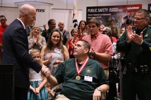 Florida Governor Rick Scott and Brevard County Sheriff Wayne Ivey today presented Brevard Sheriff's Agent John "Casey" Smith with the Metal of Heroism at a ceremony held at Harris Corporation. Harris CEO Bill Brown and about 250 Central Florida business leaders and Harris employees joined Governor Scott and Sheriff Ivey in honoring Smith, who was shot in the line of duty this past August, for his heroism. (Photo: Business Wire)