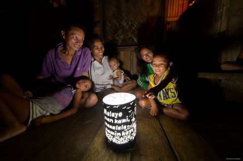 Family gathering around the solar lantern with a handmade shade (Photo: Business Wire)