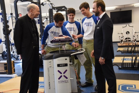Rev. Anthony McGinn and members of the Jesuit High School of New Orleans Robotics Club welcome "Morty," a Germ-Zapping Robot and gift from Jesuit alumnus Joseph Authement, SVP of Xenex. Morty will wage environmental war by destroying bacteria and potentially deadly pathogens typically found lurking inside gymnasiums, athletic locker rooms, weight training areas, shower and bathroom facilities, and even personal sports equipment. (Photo: Business Wire)