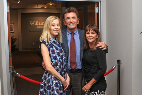 Dr. Eugene Skourtes (center), his wife, Bonnie (right) and Paige Powell (left), prepare to unveil Jean-Michel Basquiat's "The Back of the Neck" at the cultural arts initiative event at the company's headquarters in Hillsboro, Ore. March 28 (Photo: Business Wire).