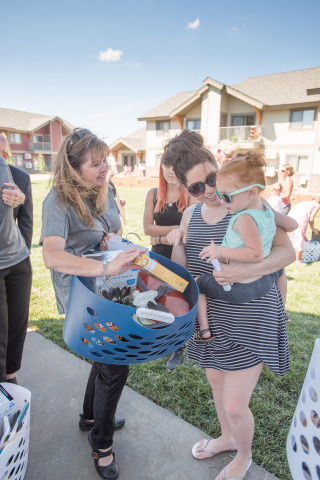 Optum Idaho Executive Director Georganne Benjamin presents a welcome gift basket donated by Optum, which invested $5.5 million to help build The Springs II, to Sherice White (holding daughter Andrea, 2) who recently moved into the new affordable housing community (Photo: Joshua Roper).