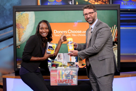 Bill Durling, vice president, global communications for Staples (left) presents Genein Letford, a teacher at New Academy Elementary School in Canoga Park, Calif. (middle) with a package of school supplies for her students, courtesy of Staples, during KCAL 9's News at Noon Thurs., Aug. 4, 2016, in Los Angeles. (Photo by Casey Rodgers/AP Images for Staples)