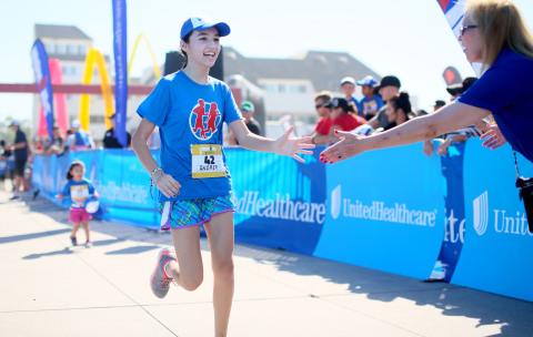 Andrea of San Diego is congratulated by Melissa Stout-Penn of UnitedHealthcare as she crosses the finish line at this morning's UnitedHealthcare IRONKIDS SUPERFROG Fun Run at Pier Plaza. UnitedHealthcare mascot Dr. Health E. Hound kicked off the fun run, and volunteers distributed medals to nearly 100 kids (Photo: Sandy Huffaker).