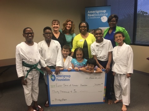 The Amerigroup Foundation grant was presented by (R-L) Tiffany Brailey and Reva Witherspoon to BridgingApps team members Cristen Reat and Cathy Foreman during Easter Seals Greater Houston’s karate and yoga play group. Easter Seals of Greater Houston karate and yoga play group participants include Dylan Lewis, Dustin Lewis, Will Ellery, Maddy Reichard, Olivia Reichard, Jonah Moore, and Eli Ellery. (Photo: Business Wire)
