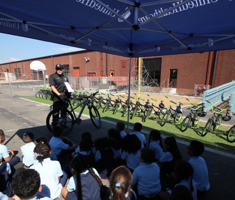 Denver Police Department Community Resource Officer Mike Borquez delivers bike safety tips to students at Rocky Mountain Prep. The kids received brand-new bicycles and helmets from UnitedHealthcare (Photo courtesy of UnitedHealthcare).