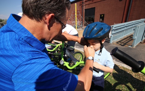 UnitedHealthcare's Marc Neely helps a Rocky Mountain Prep elementary school student put on his bike helmet for safe riding on his brand-new bike (Photo courtesy of UnitedHealthcare).
