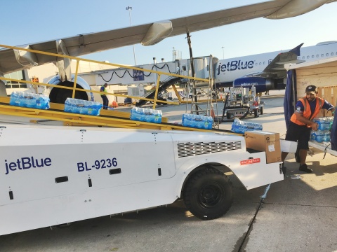 A JetBlue crewmember in Orlando loads relief supplies onto a humanitarian flight to St. Maarten. (Photo: Business Wire)