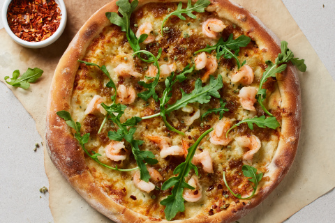 California Pizza Kitchen's Shrimp Scampi Pizza made with succulent grilled lemon-garlic shrimp, caramelized onions, Mozzarella and Parmesan cheeses atop hand-tossed dough and finished with a sprinkle of red chili, fresh arugula and wild Greek oregano. Photo Credit: California Pizza Kitchen and Waterbury Publications