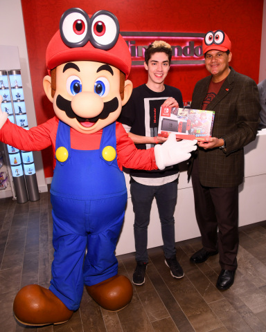 Alex P. makes the first in-store purchase of Super Mario Odyssey from Reggie Fils-Aime, President and COO of Nintendo of America, at the Nintendo NY store on October 26, 2017 at Rockefeller Plaza in New York City. (Photo by Dave Kotinsky/Getty Images for Nintendo of America)