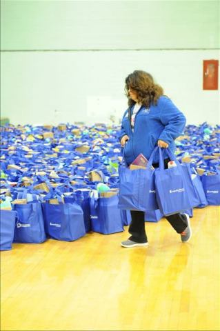 A UnitedHealthcare employee helps sort bags of food, coats, toys, holiday trimmings and essential living items in Flint during a Holiday Hope event hosted by UnitedHealthcare and Magic Johnson Foundation on Saturday, Nov. 18, at Flint Northwestern High School. (Photo: Ken Jones)