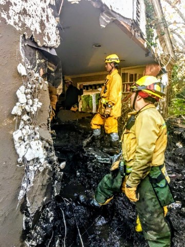 Firefighters lend a hand to the Grokenberger family who returned to their Montecito home in search of personal items following the January 9 mudslides. The residence is a total loss after a 5-foot mudflow slammed through the north wall of their two-story home, filling the first-floor to the top of the front doorway. (Photo: Business Wire)