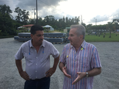 Jose Miguel Ramirez (left), General Manager of Recyplast, leads a tour of Recyplast's manufacturing operation in Siquirres, Costa Rica in an event commemorating the 25th Anniversary of this pioneering enterprise. Renato Acuña, President of Dole Fresh Fruit, comments on ideas for future plant expansion. In the background, plastic recycled corner boards ready for shipment to fresh fruit exporters.