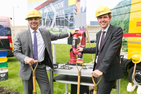 Mike Parra, CEO for DHL Express Americas and Matthias Heutger, SVP, Global Head of Innovation & Commercial Development at DHL, celebrate the groundbreaking of DHL's Americas Innovation Center with Sawyer, a collaborative robot that supports production and DHL warehouse staff by automating repetitive tasks. (Photo: Business Wire)