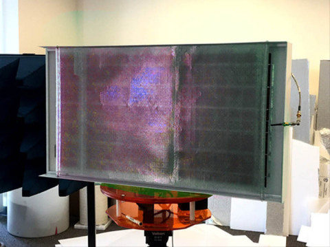 An aperture engine prototype shows a nearly transparent antenna array of fractals letting light shine down onto solar cells. Batteries, a computer, and a transmitter/receiver lie flat on the other side (note feed). The same area that collects power also acts as an antenna, without a separate power source or separate units. (Photo: Business Wire)