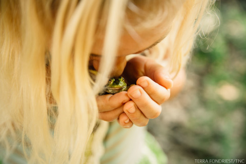 Third Place: FROG HUG | ARKANSAS "Down at the mud puddles on our road, we found several young bullfrogs hopping around. Up on our hilltop, wet spots are few and far between, so our mud puddles are home to a constant flow of tadpoles, frogs and toads. My daughter loves all critters, her goal is to create a wildlife rehab center someday. She constantly inspires me with her care towards every living thing." Photo by Terra Fondriest, St. Joe, Arkansas, USA.