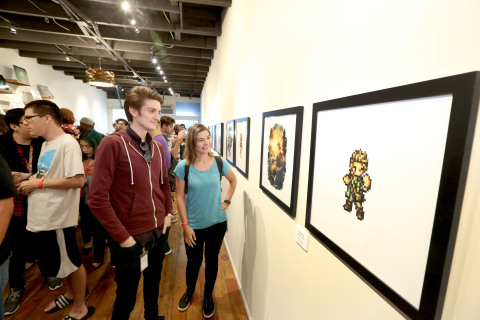 In this photo provided by Nintendo of America, fans look at artwork of Octopath Traveler and enjoy a launch celebration at iam8bit Gallery in Los Angeles. Octopath Traveler is now available in Nintendo eShop on Nintendo Switch and is available at retailers on July 13. 