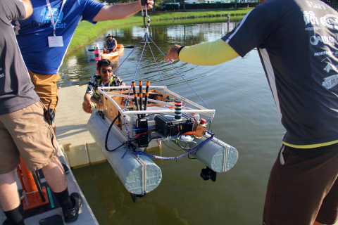 A RoboBoat team gingerly lowers their AV boat into the water. (Photo: Business Wire)