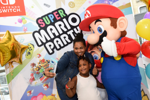 In this photo provided by Nintendo of America, Shirley M. and Gabriella A., 5, of New York, NY, celebrate the launch of the Super Mario Party and Luigi’s Mansion games by posing with Mario during a special event at the Nintendo NY store in Rockefeller Plaza. An action-packed party game with 80 interactive mini-games, Super Mario Party is now available for the Nintendo Switch system. The spooky classic game Luigi’s Mansion will be available for the Nintendo 3DS family of systems on Oct. 12. (Photo: Business Wire)