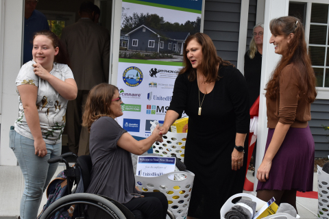 Woodland Place residents Jennifer Syer (center) and Alyssa Whatley (left) receive a welcome basket filled with household items and healthy foods from UnitedHealthcare's Melanie Osment (center right) and Oceana's Home Partnership's Kittie Tuinstra (far right) (Photo: Nick Azarro)